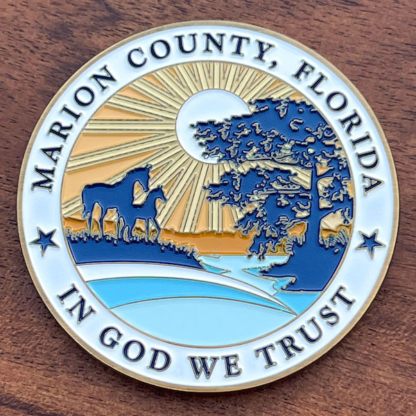 Photo of a Marion County Florida custom coin  showing horses, sunset, trees and a stream