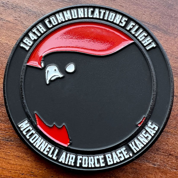 Round black dyed metal challenge coin representing the Air Force's 184th  Communications Flight. 