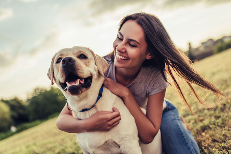 photo of young woman hugging large white dog with floppy ears