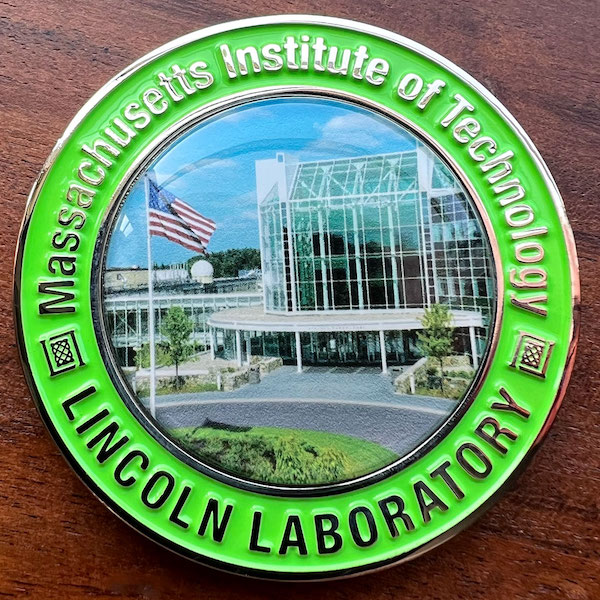 Round silver challenge coin representing MIT's Lincoln Laboratory. 