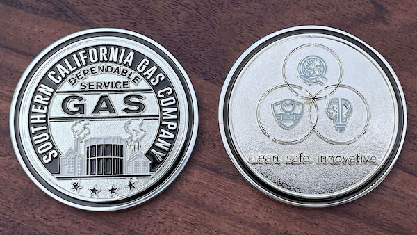 Front and reverse side of a polished silver challenge coin belonging to the Southern California Gas Company. 